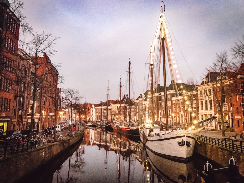 A sunset view of a canal street in Groningen and the boat up front has been decorated with big white bulbs