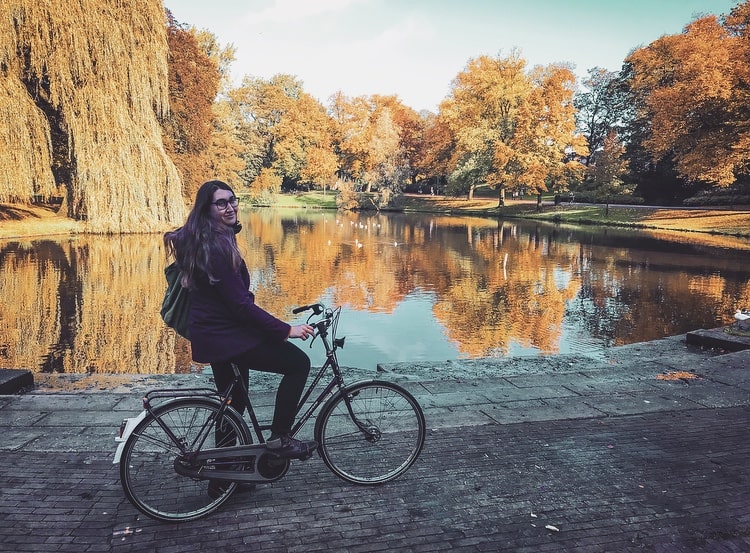 A woman on a bike stopped in front of a pond at Noorderplantsoen in Groningen, Netherlands