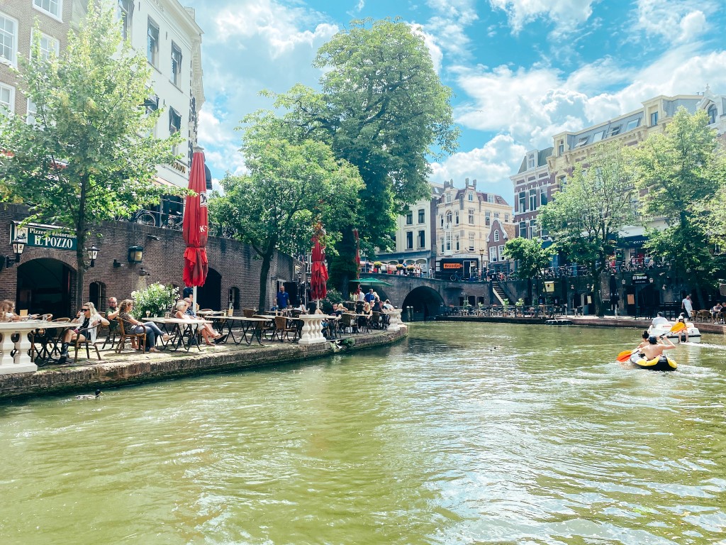 Utrecht city center on a beautiful afternoon with people kayaking in the canal and others drinking in the sun