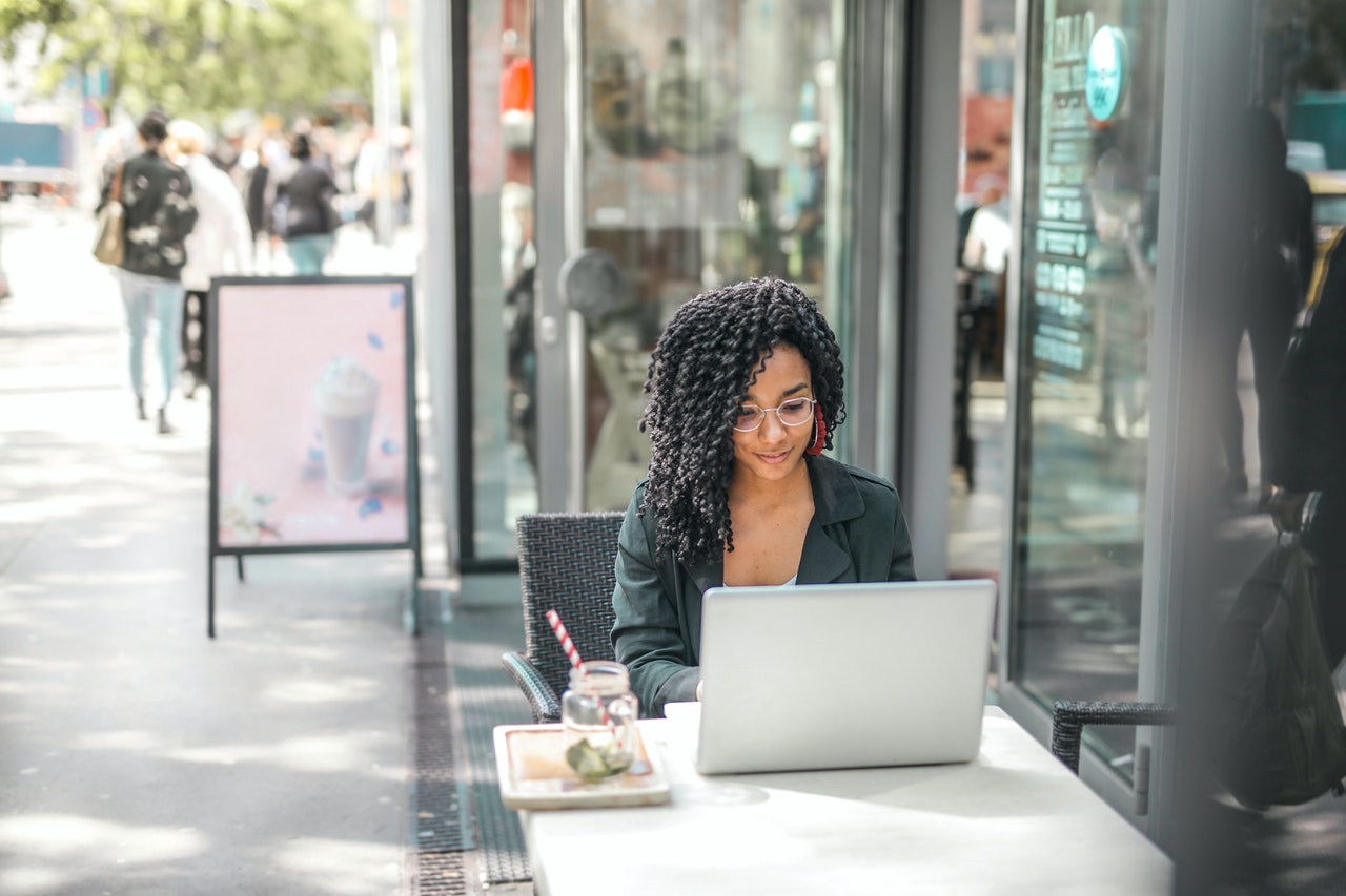 Woman working on her computer outside at a cafe in the afternoon