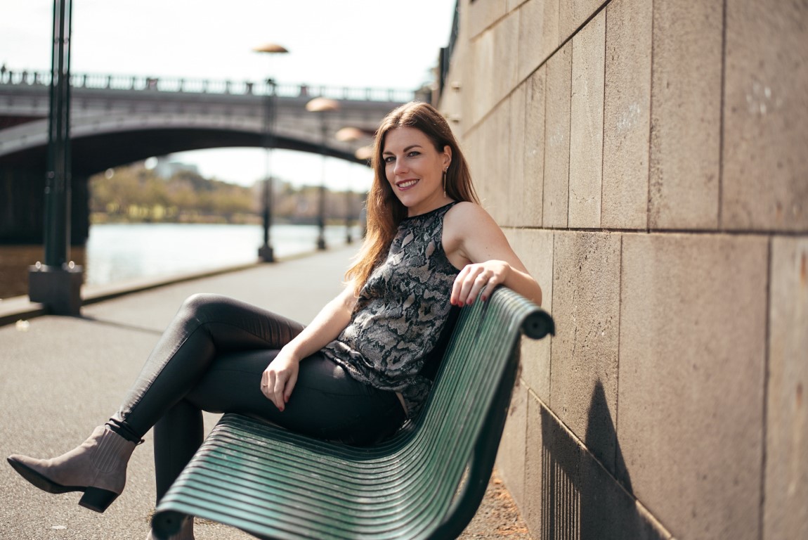 A woman from the Netherlands living abroad in Australia sitting on a bench and smiling at the camera
