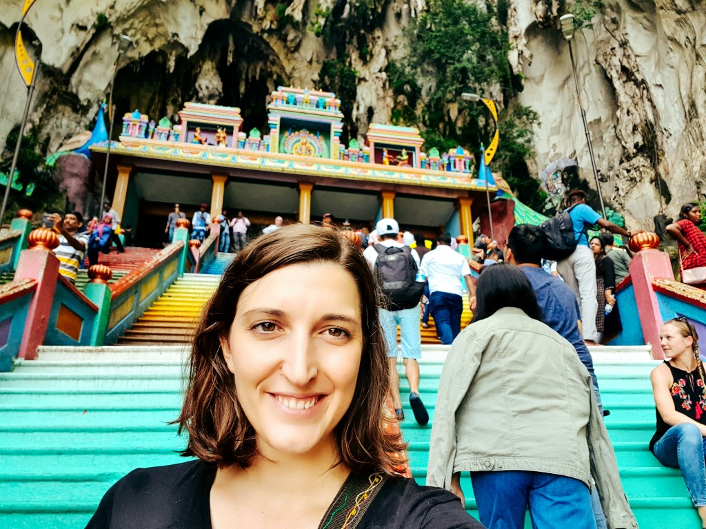 A woman taking a selfie on the rainbow stairs leading up to Batu Caves in Kuala Lumpur