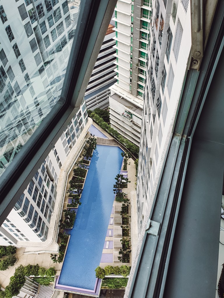 a view out of a side window of a high rise to the swimming pool nearly 20 floors below