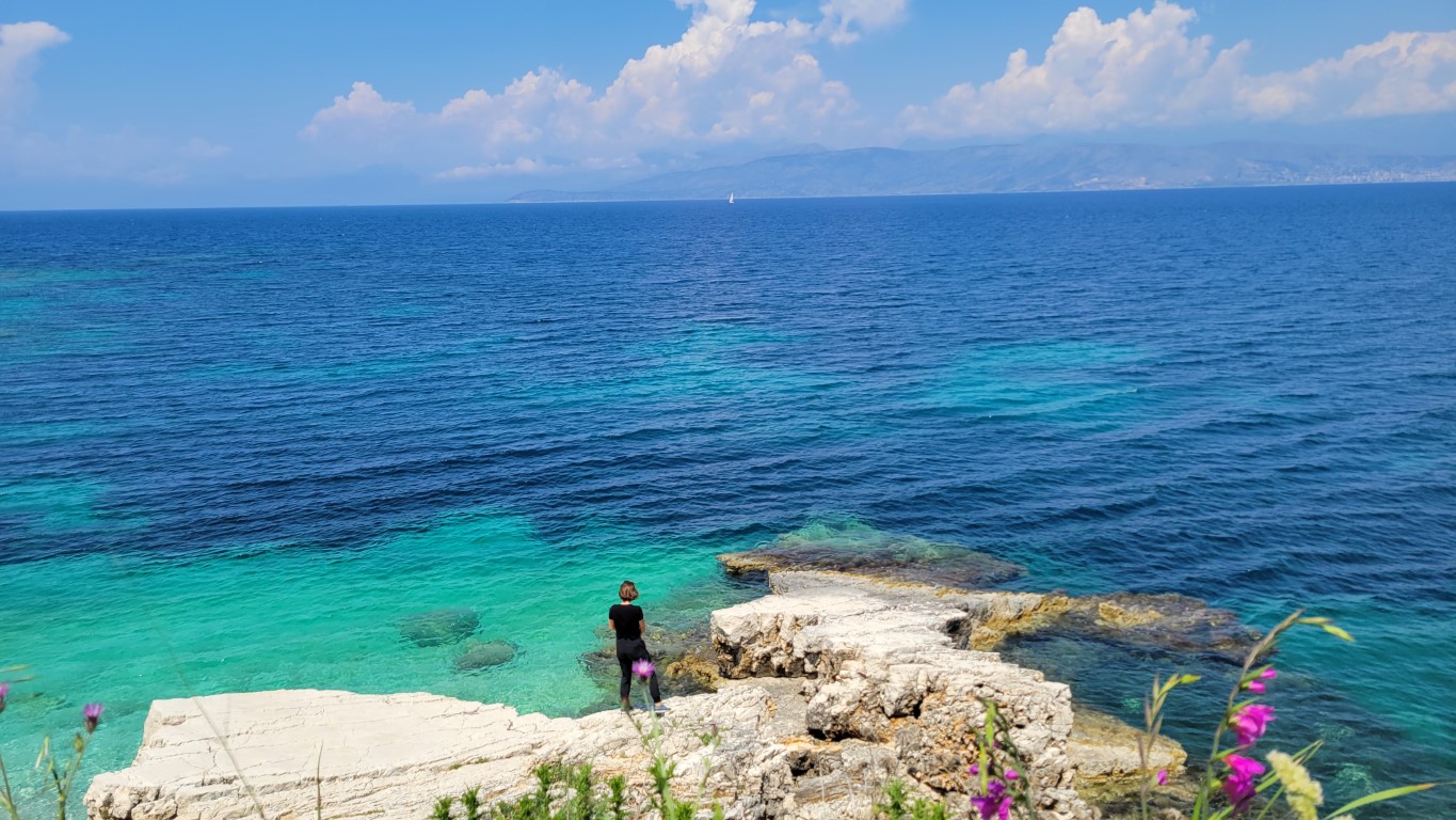 a woman standing on tocks overlooking the Ionian Sea in Corfu, Greece