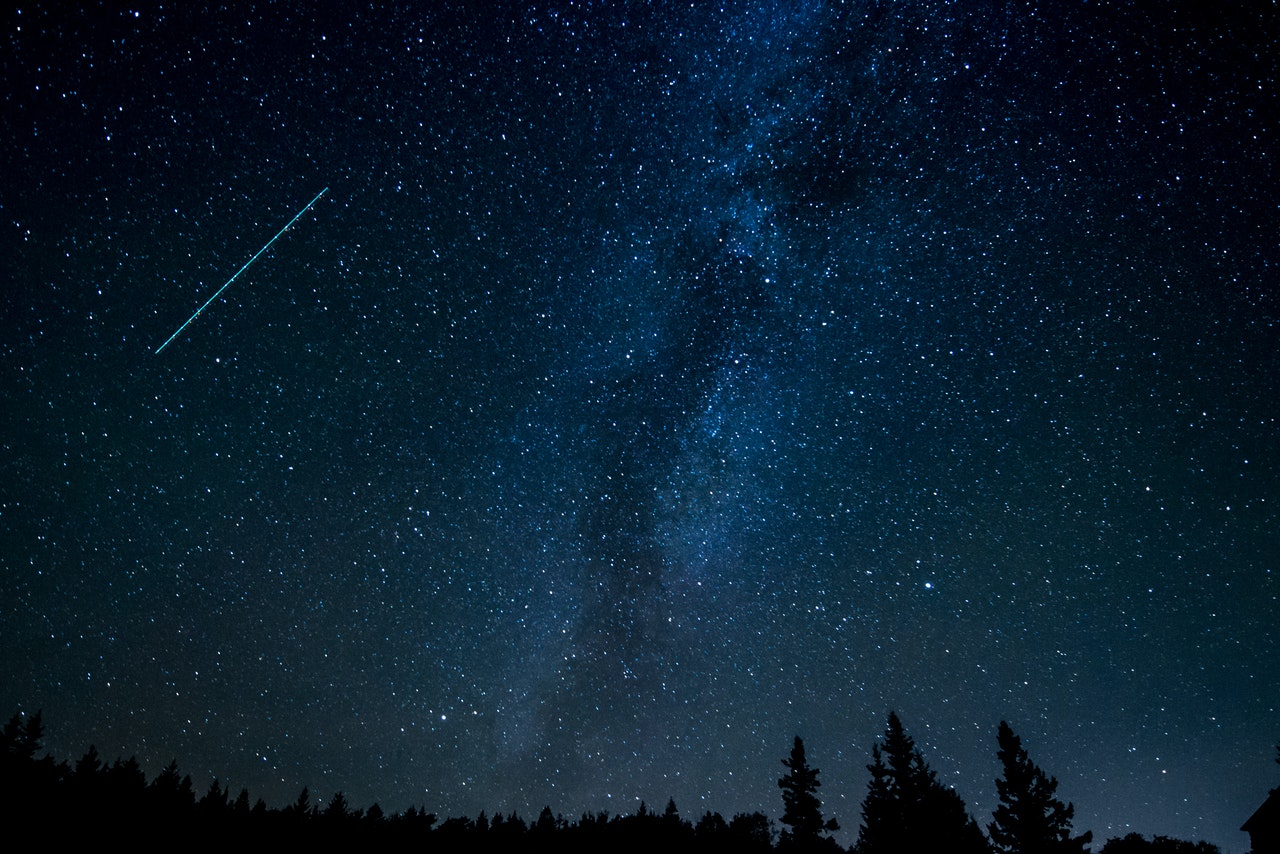 a clear night sky littered with stars and a shooting star