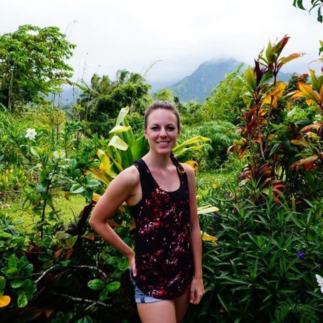 A woman smiling in a lush green jungle