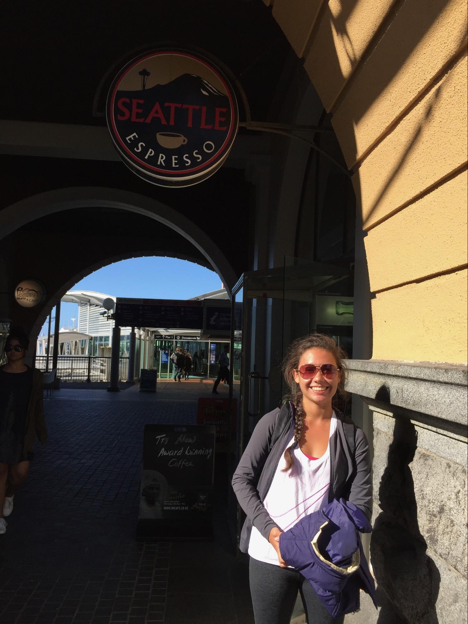 A woman posing in front of the "Seattle Espresso" coffee shop in Auckland, NZ.