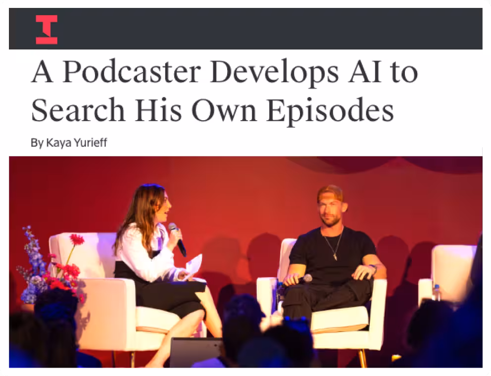 Two people seated on stage in white armchairs during a podcast or interview event, with a red background and audience silhouettes visible.