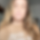 Blurred portrait of a person with long hair wearing a beige top.