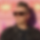 Blurred image of a person wearing sunglasses and dark clothing.