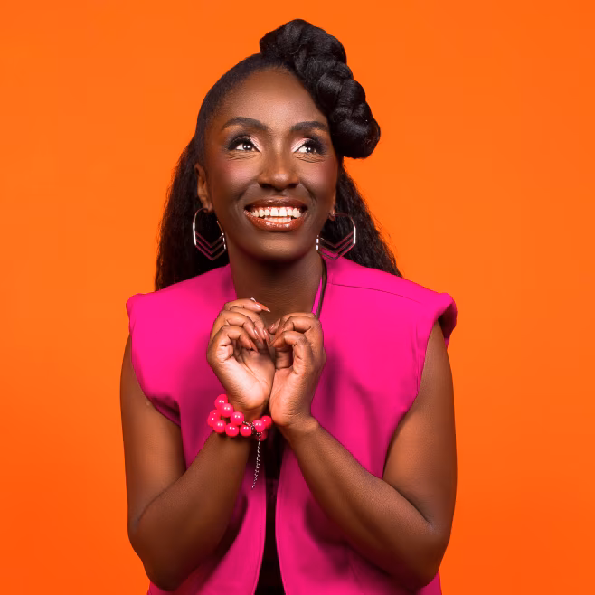 Smiling woman in a bright pink sleeveless top with braided hair against an orange background.