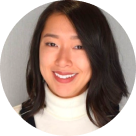 Portrait of a smiling woman with long black hair wearing a white turtleneck.