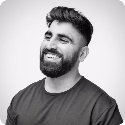 Smiling man with a thick beard and short dark hair wearing a dark t-shirt, looking slightly to the side.