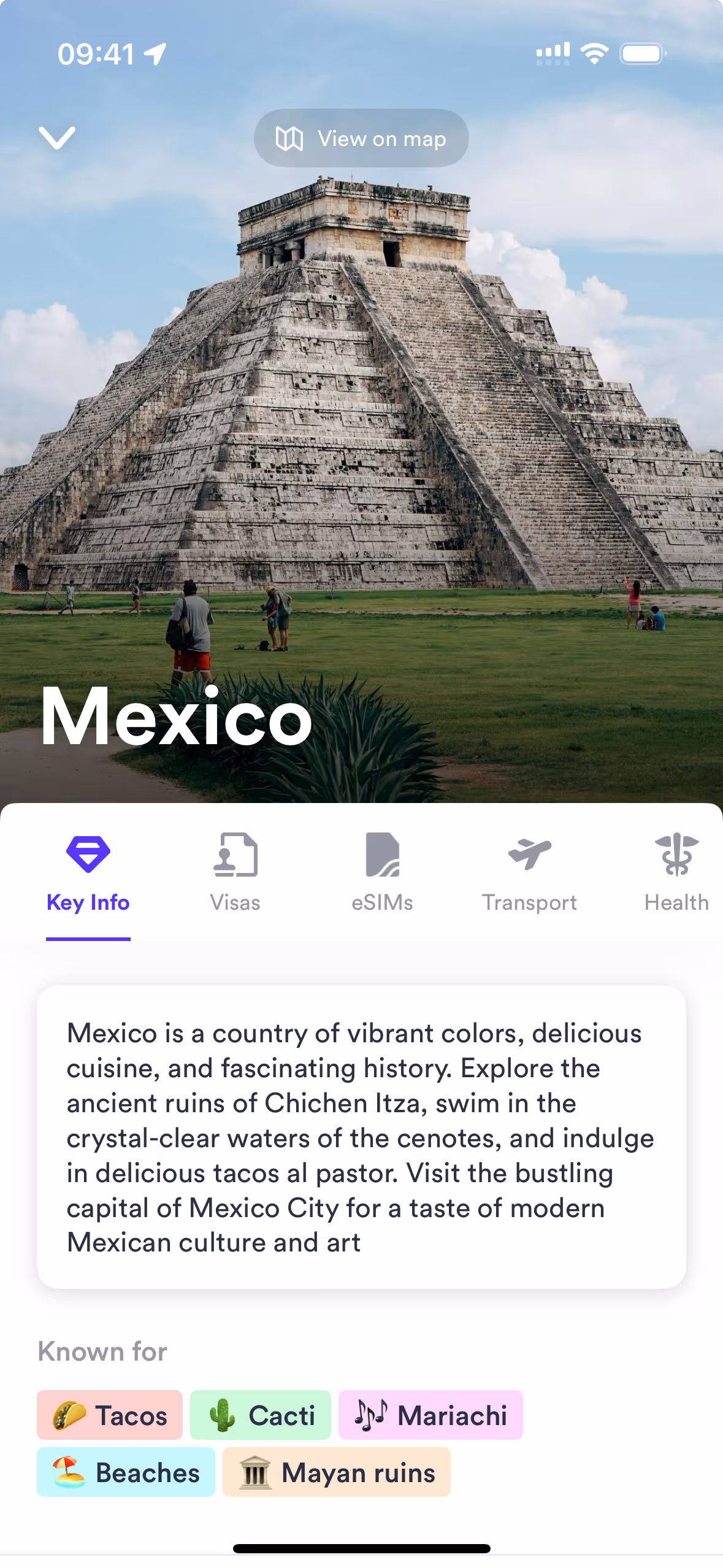 Ancient stepped pyramid of Chichen Itza with visitors on green grass under a partly cloudy sky, on a Skratch app screen about Mexico.