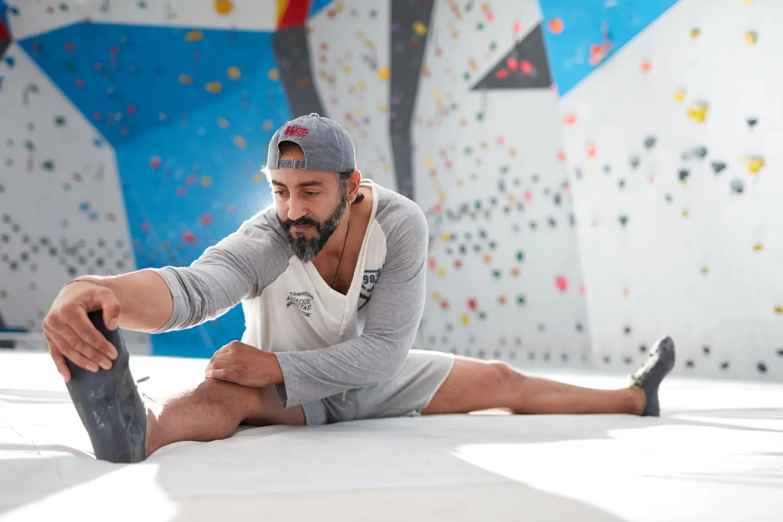 Determined man touching toes against climbing wall