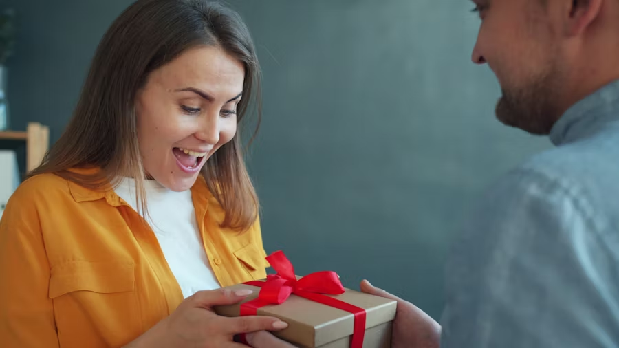A man hands a smiling woman a gift-wrapped box.
