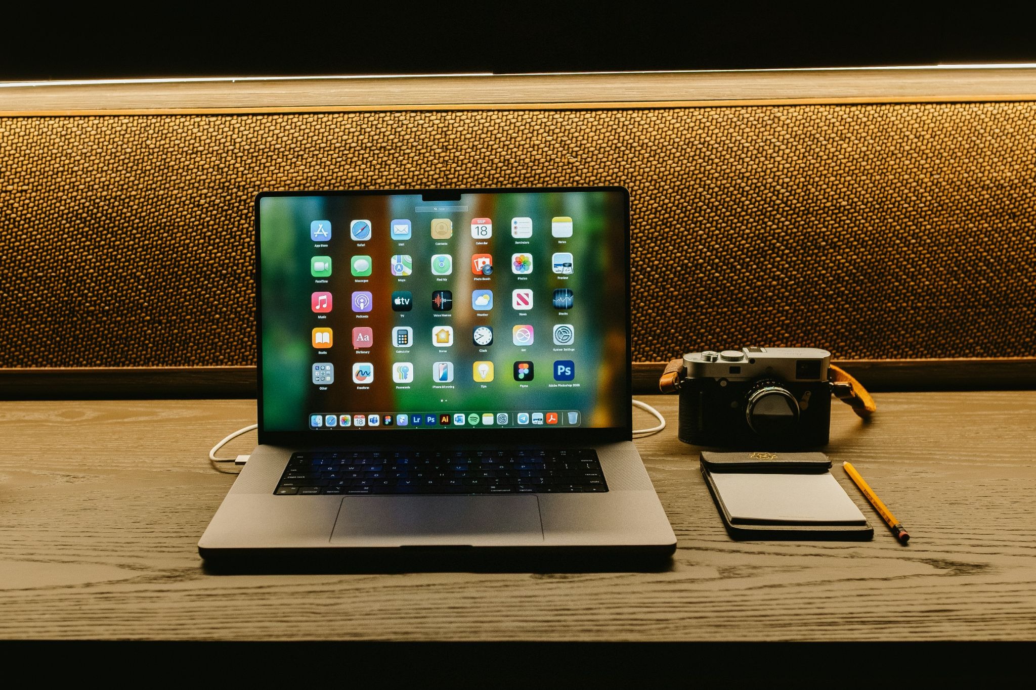 A laptop, camera and notepad demonstrating organized tech.