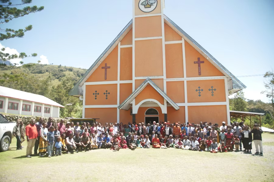 A group of community church volunteers gathered outside a church on a sunny day.