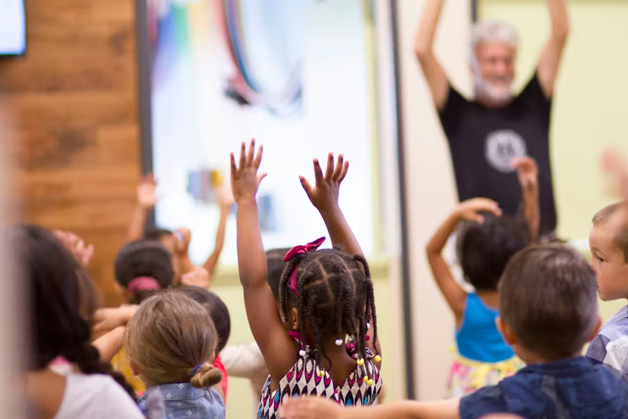 A group of Sunday school children with their hands in the air.
