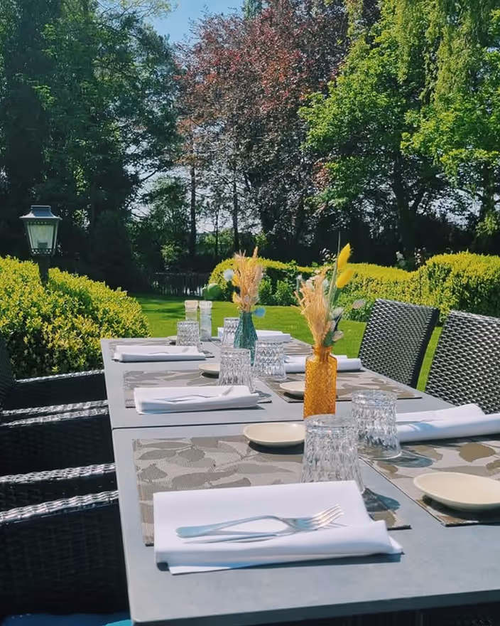 Gedekte tafel op het terras van Restaurant d’Urville met zicht op de groene tuin in Torhout