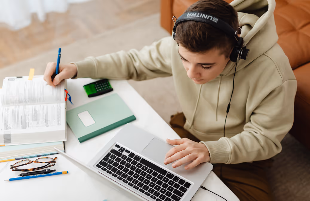 Student typing at a table with books