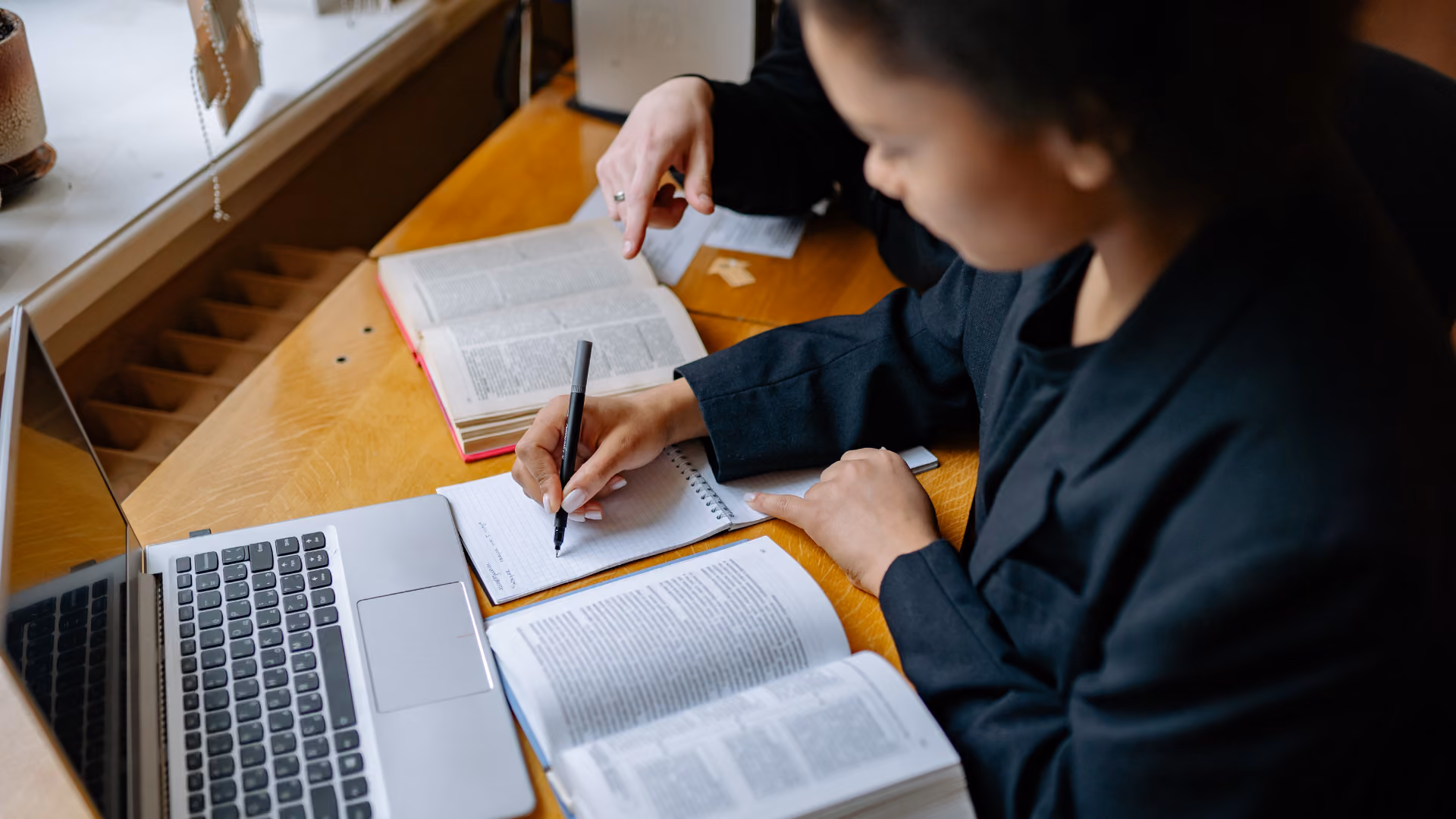 Image of a student taking notes at a desk