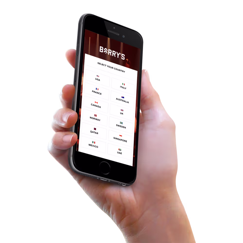 Hand holding iphone with Barry's Bootcamp website mockup on screen.