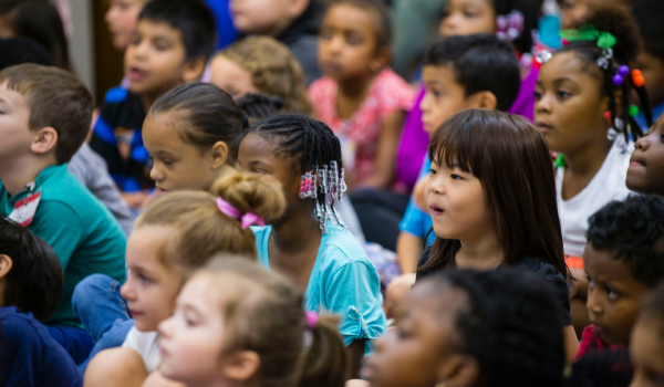 Young children gather together for a presentation.