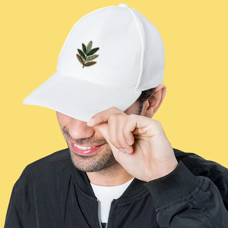 A man wearing a white hat with a green leaf on it.