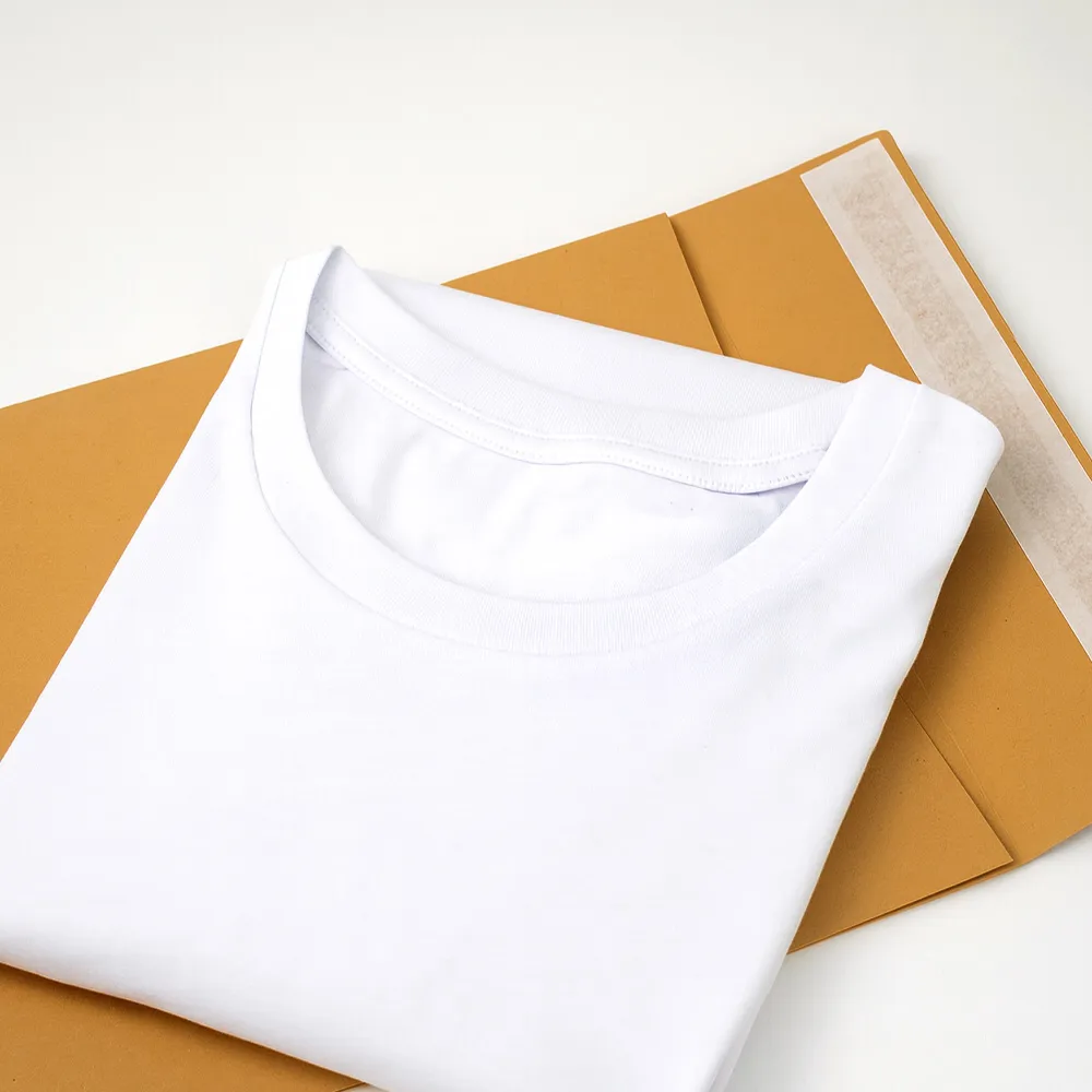Folded white crew-neck T-shirt placed on top of two brown kraft paper envelopes.