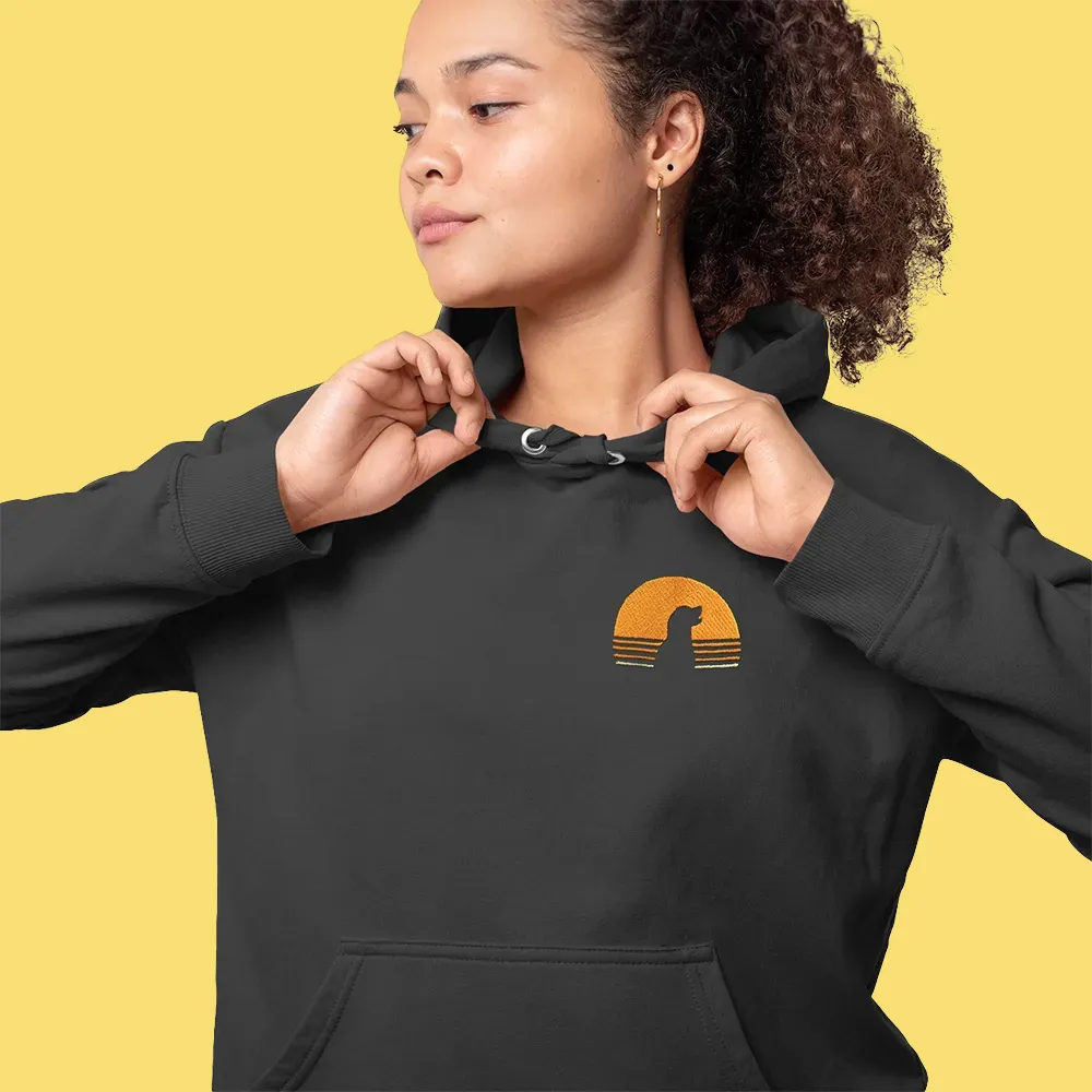 Woman wearing black hoodie with orange sunset and dog silhouette design on front pocket area.