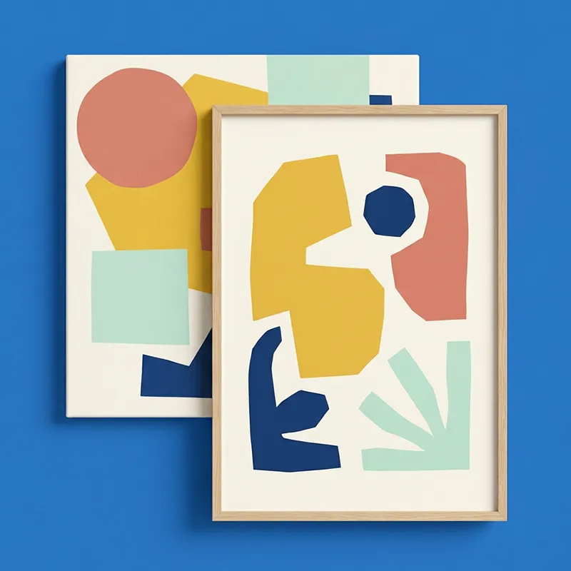 Two modern abstract art prints with irregular shapes in muted colors including mustard yellow, terracotta, navy blue, and light mint green on off-white backgrounds, one framed in light wood and overlapping the other, set against a solid bright blue backdrop.