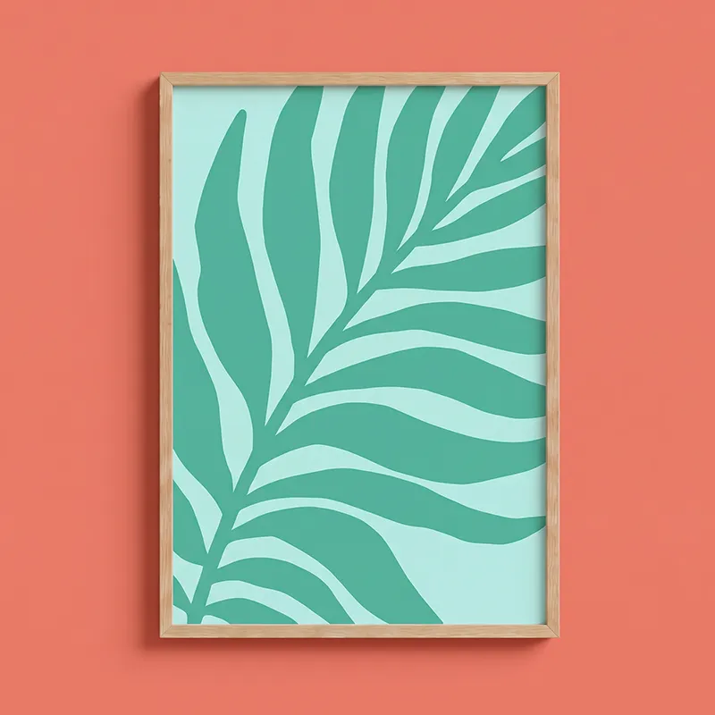 Wooden frame with a minimalist green leaf pattern on a light blue background, displayed on a coral-colored wall.