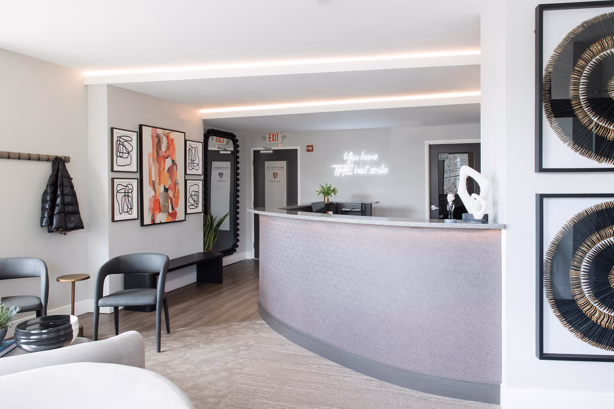 A reception area with chairs, a counter and pictures on the wall.