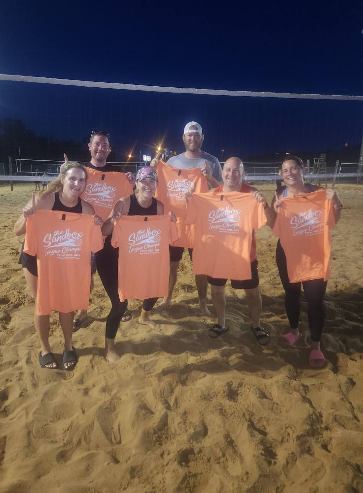 picture of a group of volleyball players wearing the sandbox volleyball logo t-shirts