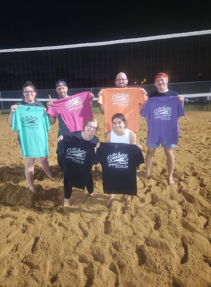 picture of a group of volleyball players wearing the sandbox volleyball logo t-shirts