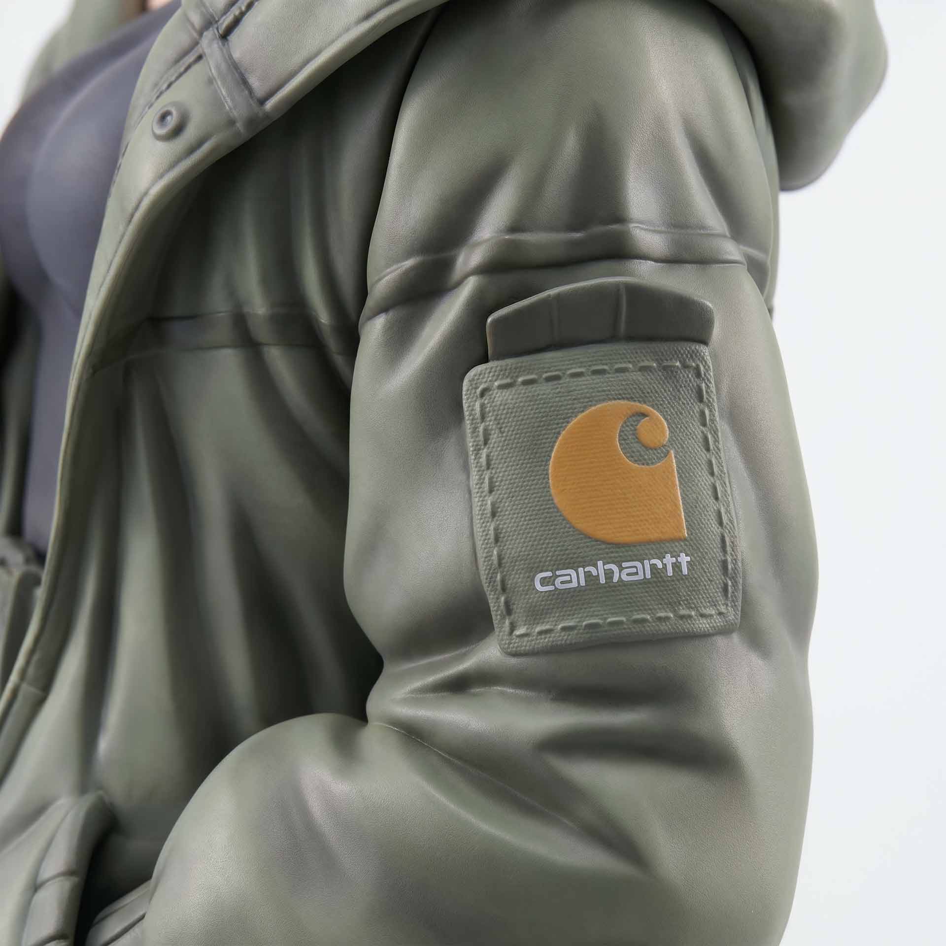 Close-up of a green Carhartt jacket sleeve with the brand's brown and white logo patch.