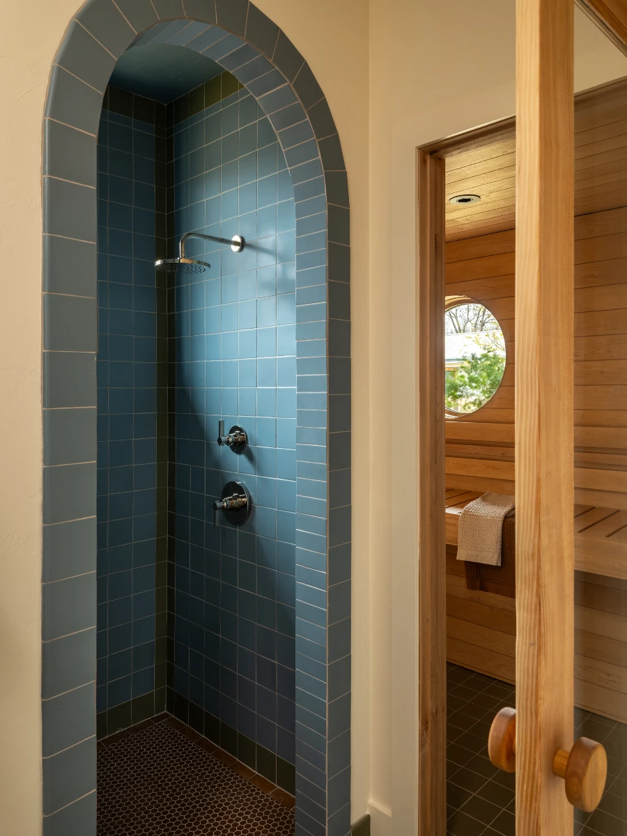 A blue-tiled walk-in shower next to a wood paneled sauna