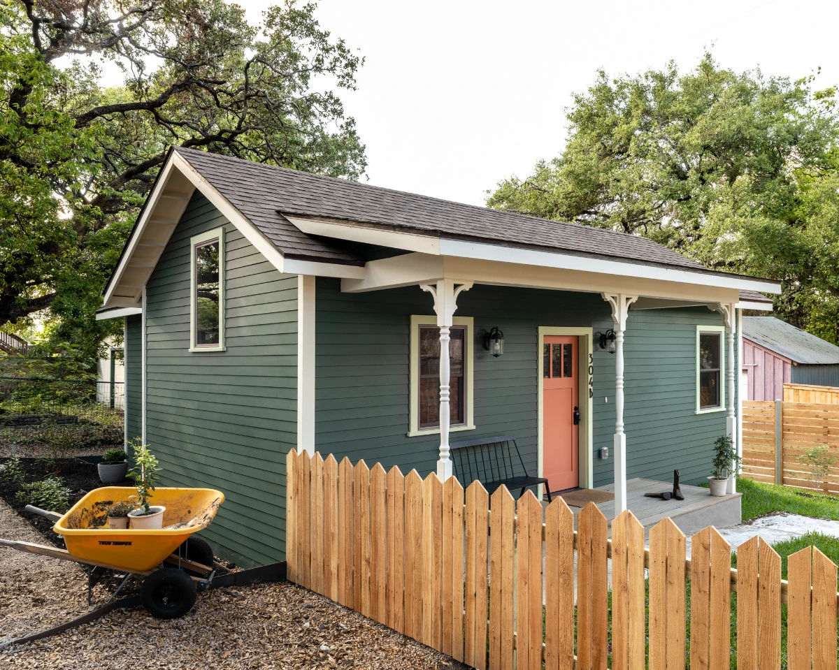 The Back House exterior, showing dark green siding accented by a salmon-colored front door.