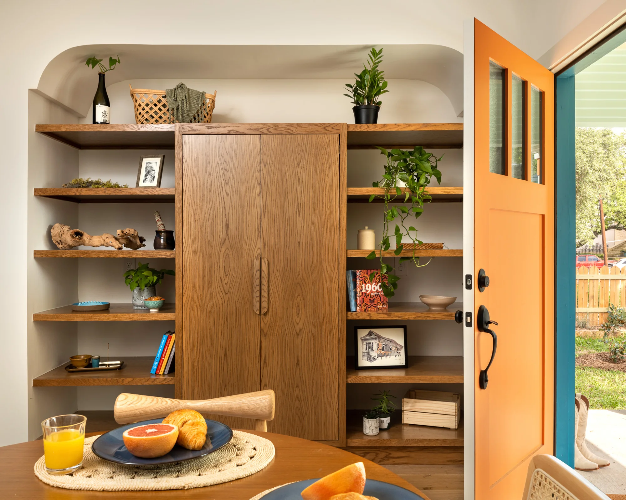 The dining area of SOCO Duo, complete with wood built-in shelves and a table stocked with fruit and pastries