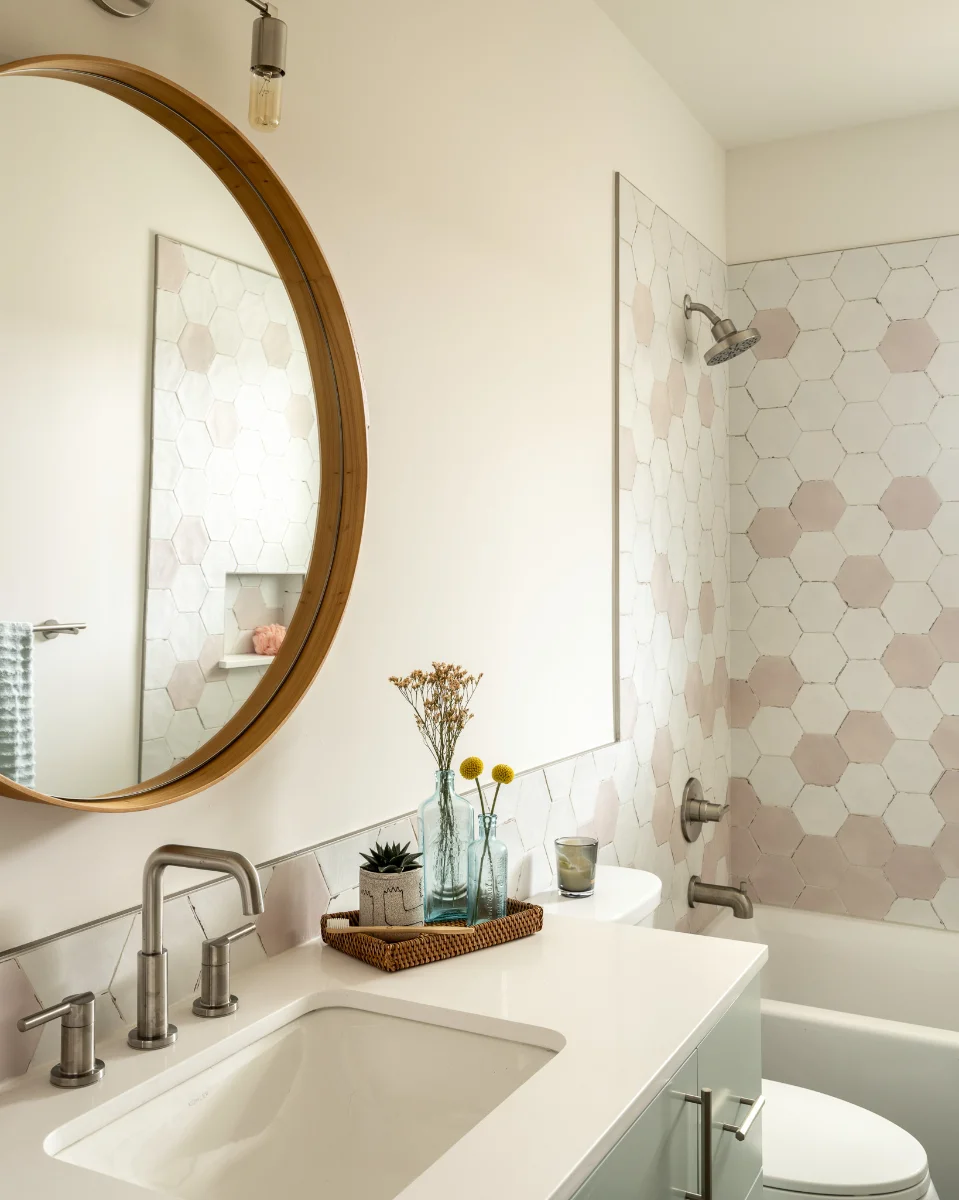 A bathroom in SOCO DUO with a hexagon-tiled shower-bath combo and a large round mirror