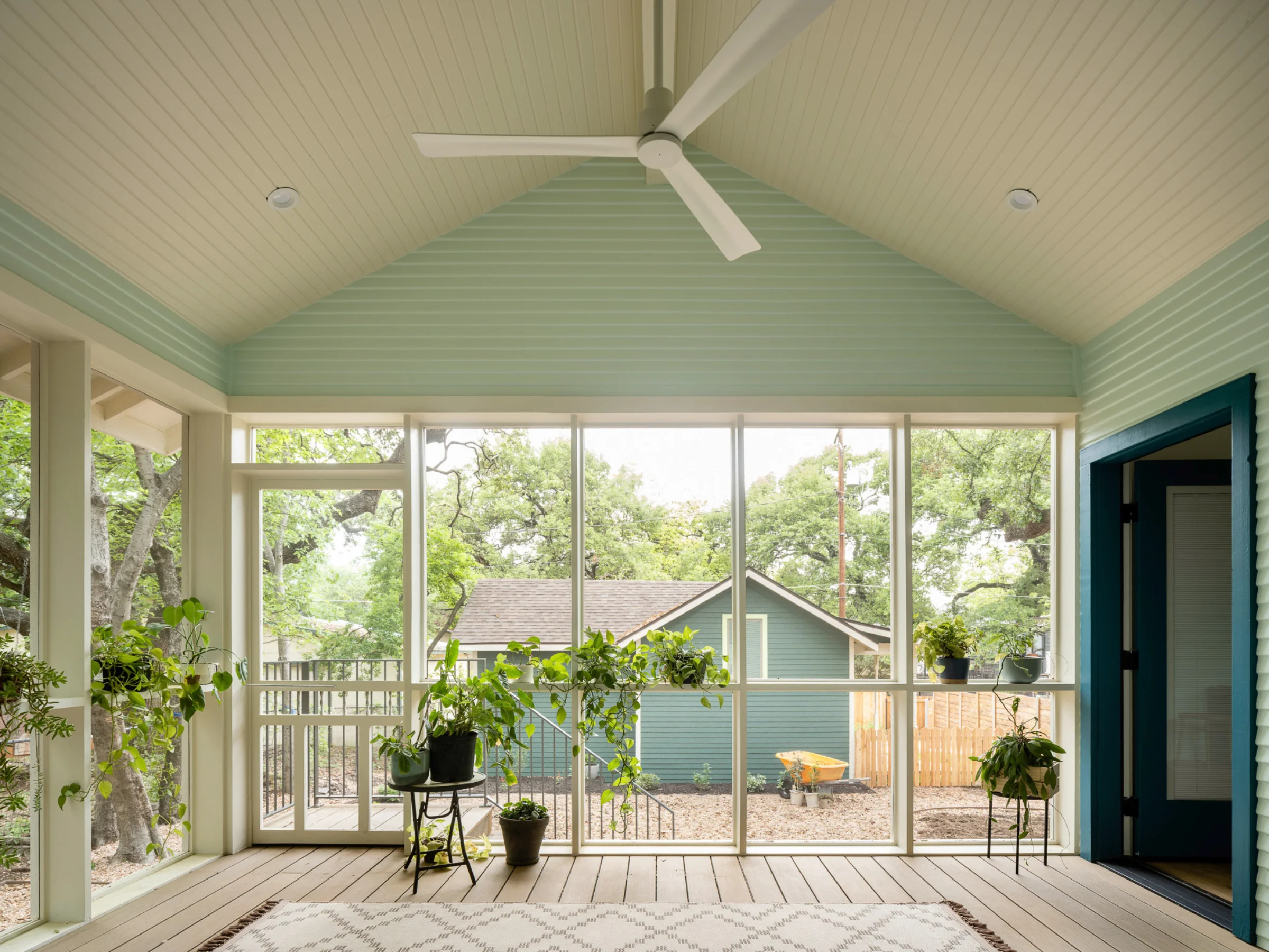 SOCO Duo's pale green sunroom with a handful of healthy houseplants. A yard can be seen through the windows.