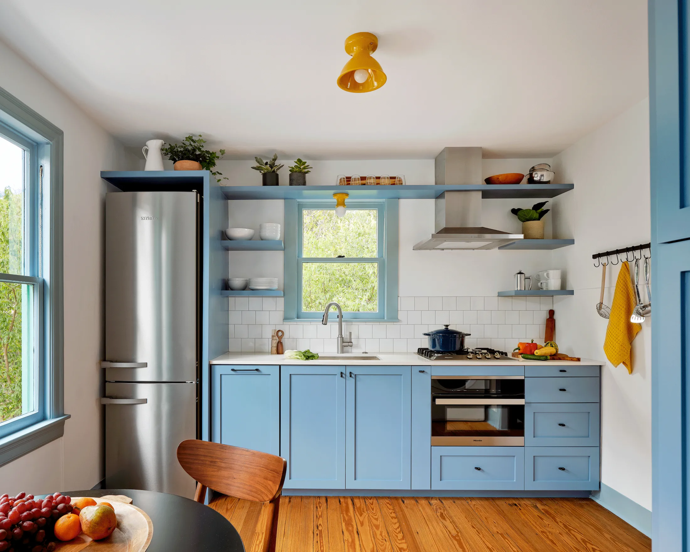 The Guesthouse East kitchen, complete with light blue cabinetry, primary color accents, and a stainless steel fridge.