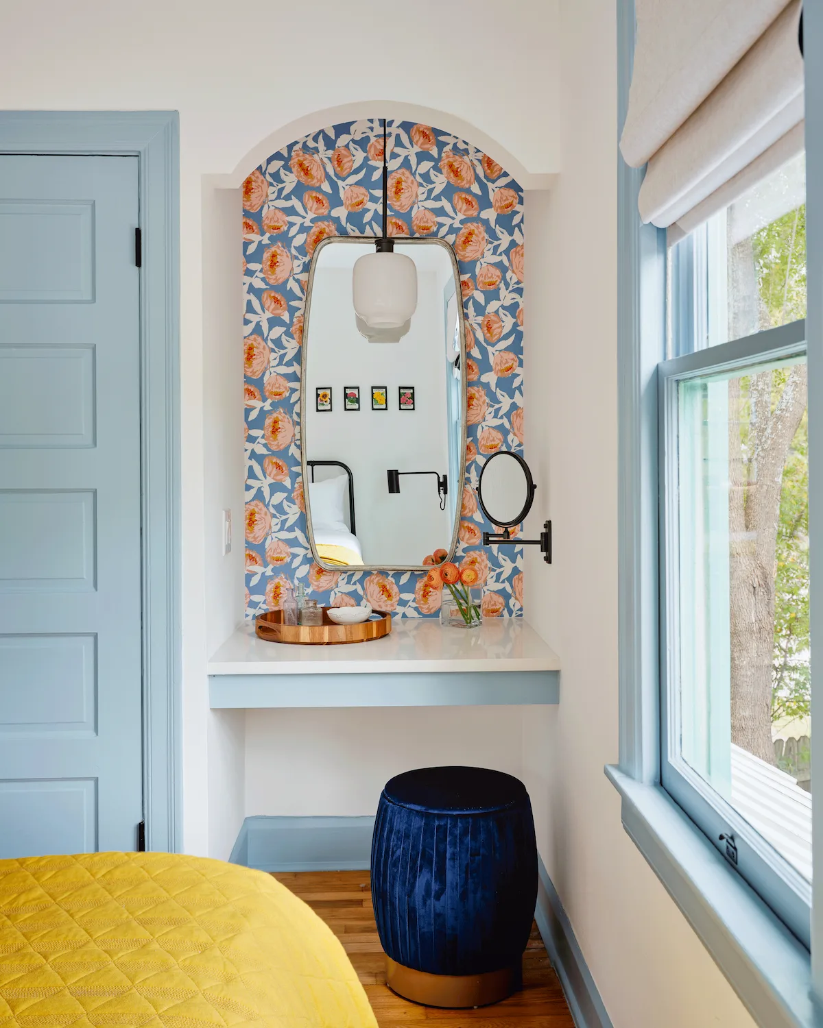 In Guesthouse East, a built-in vanity is accented with a bold blue and pink floral wallpaper.