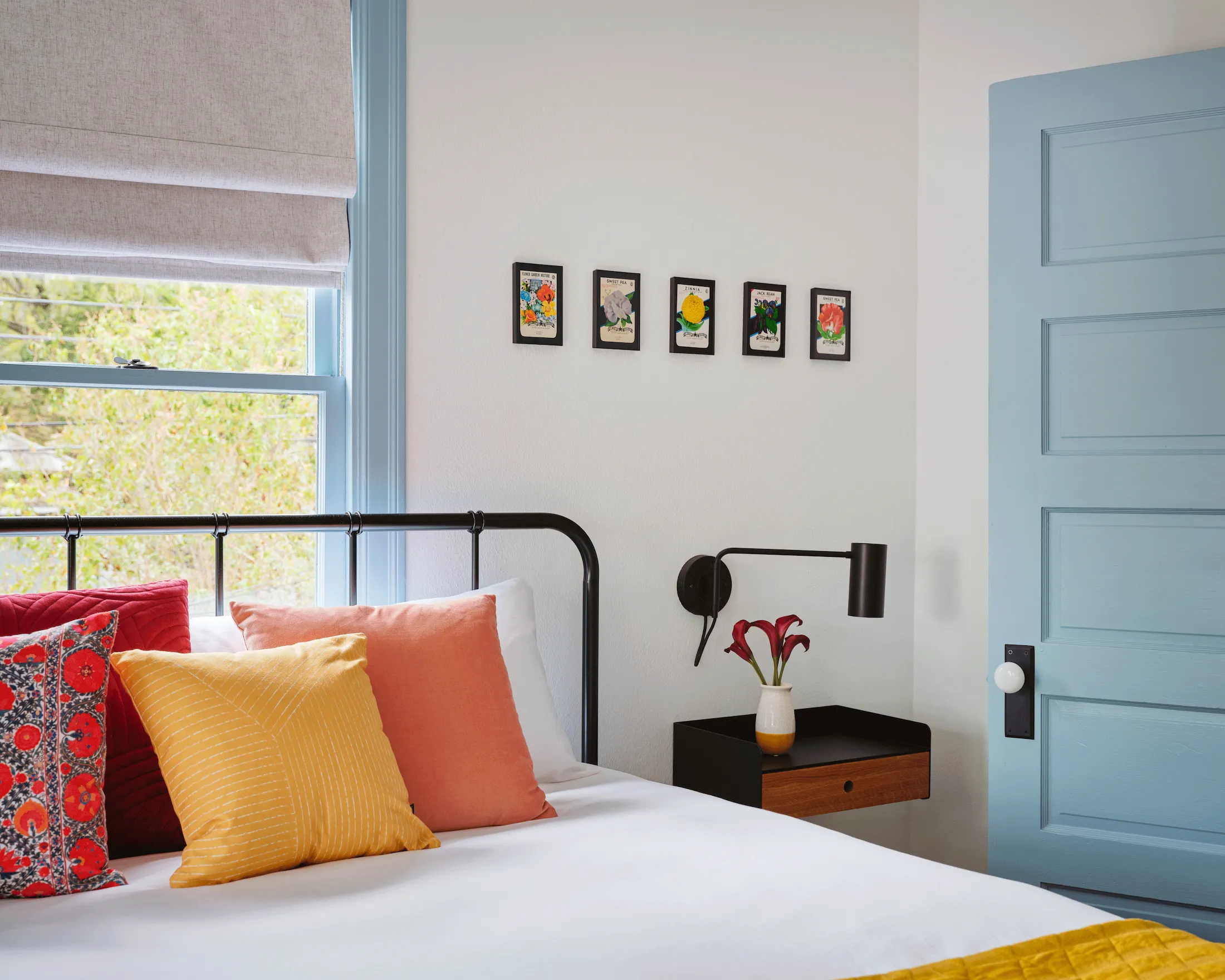 An alternate angle of a bedroom in Guesthouse East, showing clean white walls accented by light-blue woodwork and colorful decor.