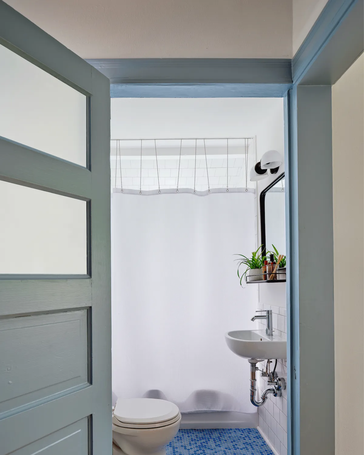 The bathroom in Guesthouse East features white walls and fixtures accented by blue hexagon tile.