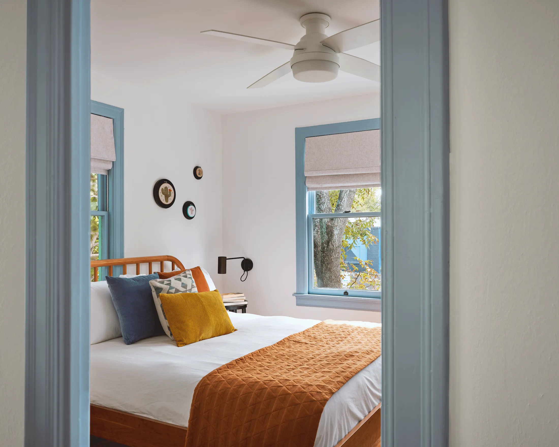 A view of a bedroom in Guesthouse East. A central wood bed is set with clean white bedding accented with warm-hued pillows.