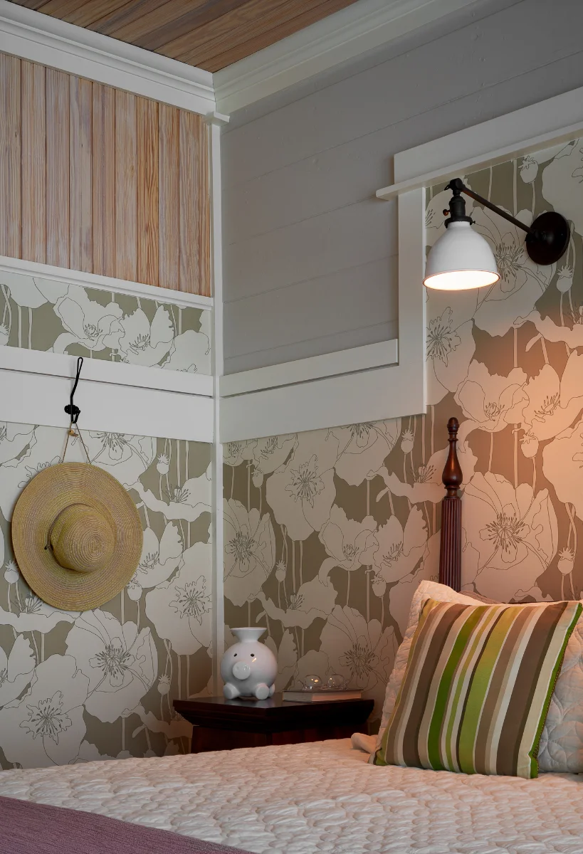 A soft, neutral-toned corner of a Wende Bungalow bedroom. The walls feature a combination of wood paneling and floral wallpaper.