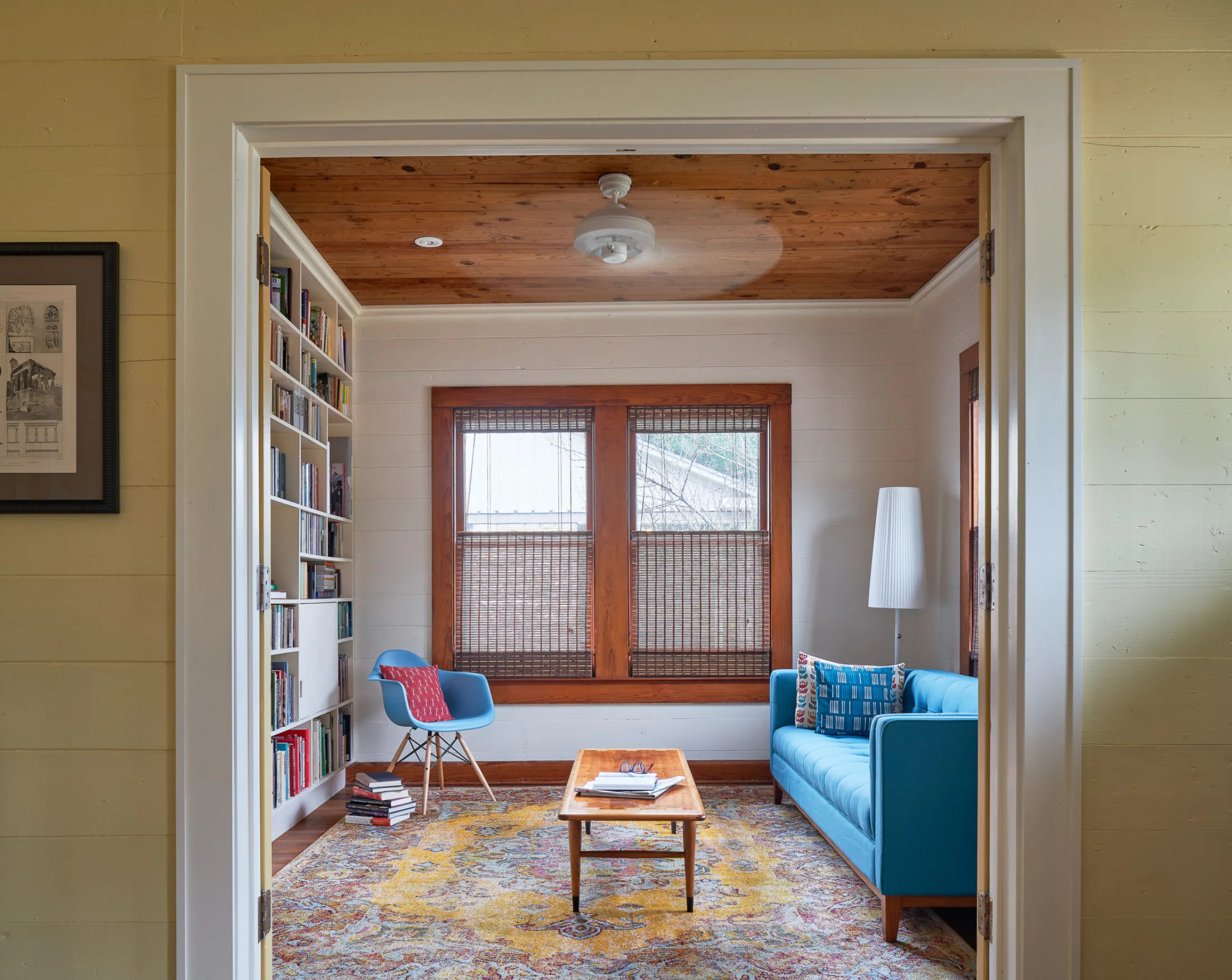 The doorway into a living and reading space in Wende Bungalow. A welcoming light blue couch appears across from modern built-in bookshelves 