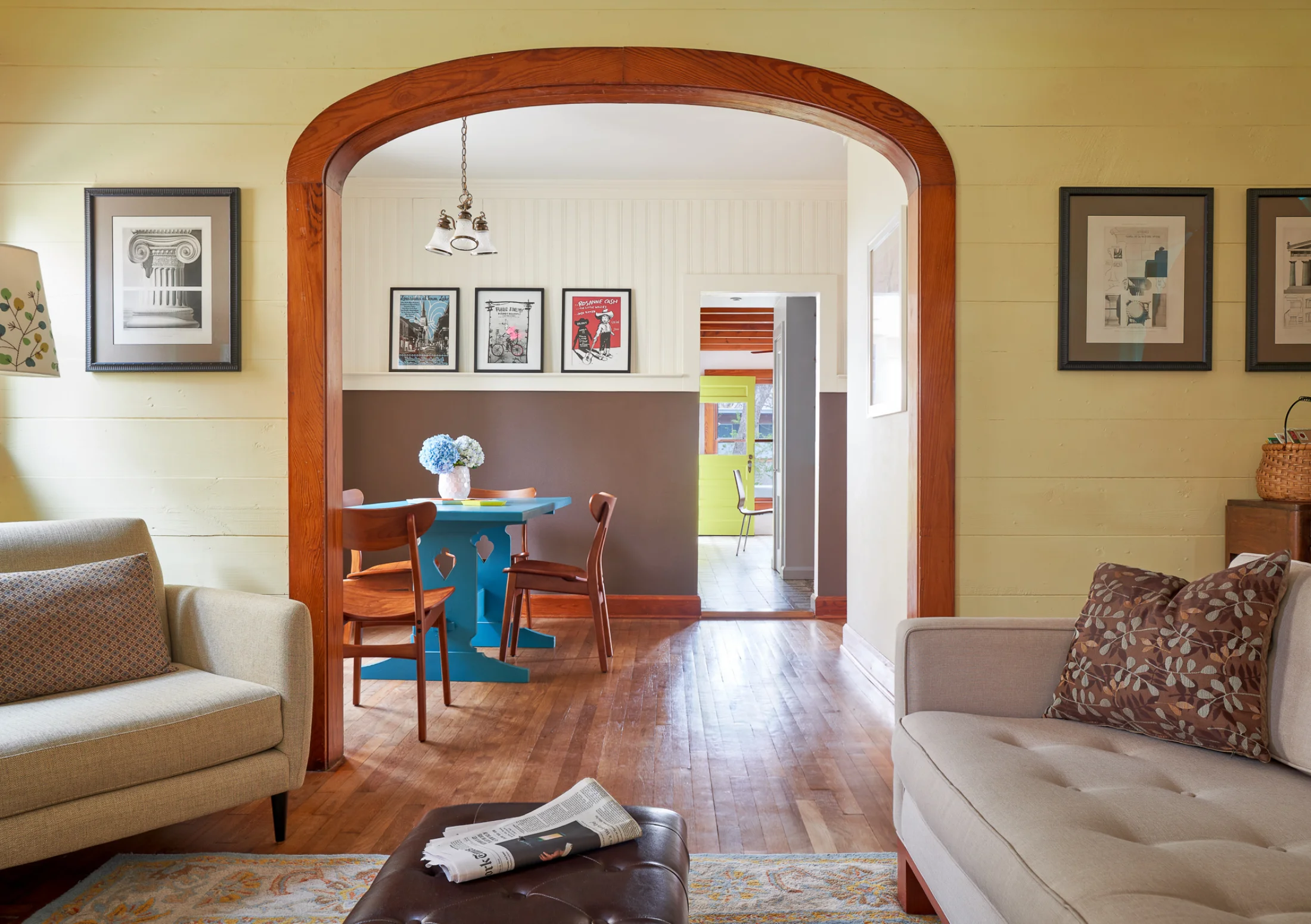 A curved wood arch frames the Wende Bungalow dining room. Funky, whimsical furniture and decor assembled throughout. 
